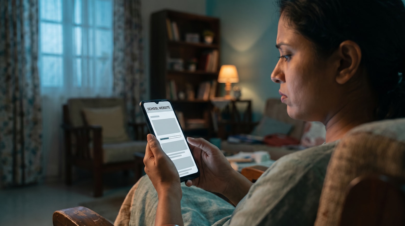 A parent checking a school website on a mobile phone while the page is still loading